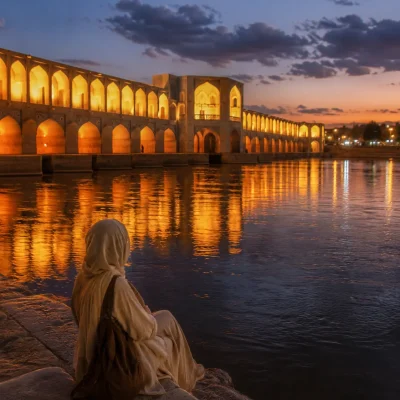 Traveler sitting by Khaju Bridge at dusk in Isfahan Iran