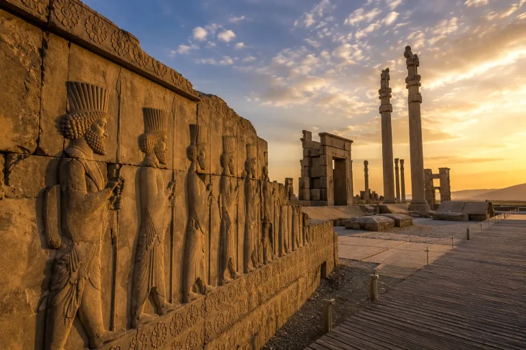 Stone reliefs and monumental columns at Persepolis in Iran during sunset