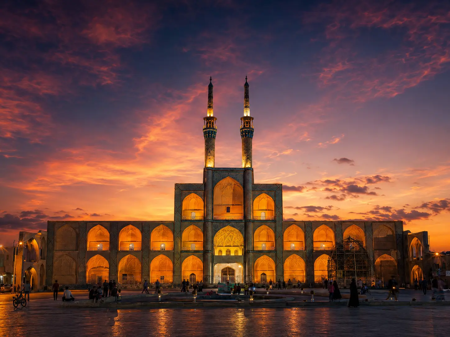 Amir Chakhmaq Complex in Yazd at dramatic sunset with illuminated arches and twin minarets